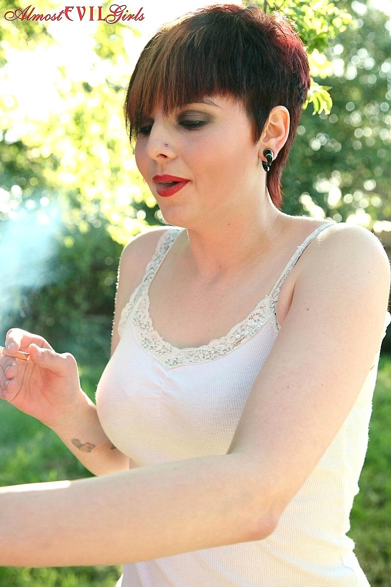 Short haired girl Morna flashes tits and twat while smoking in backyard